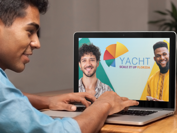 photo of a man on a computer with the YACHT logo on the screen
