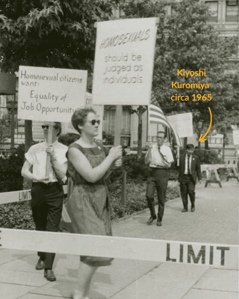 A photograph of 4 individuals picketing with signs that read "Homosexuals should be judged as individuals," and "Homosexual citizens want equality of job opportunity." The figure furthest from the camera has an arrow pointing to him to indicate this is an early image of Kiyoshi Kuromiya in the back of the picket line at the Annual Reminders