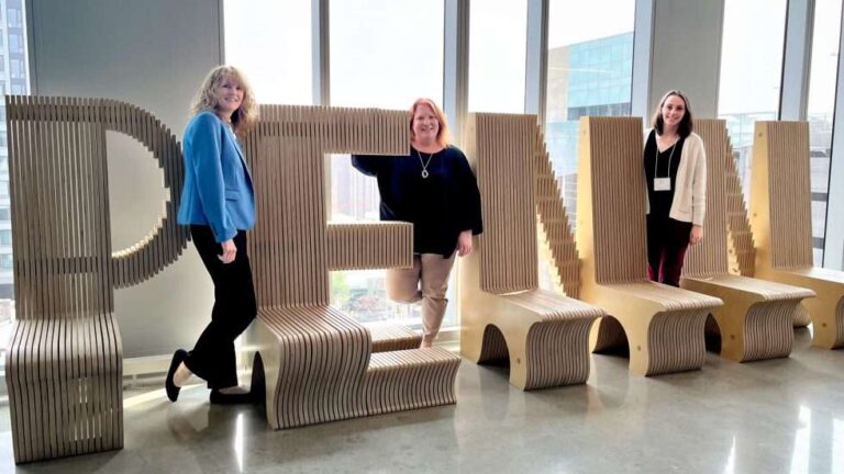 Photo of three team members from ProChange Behavior Solutions standing in front of a wooden Penn sign