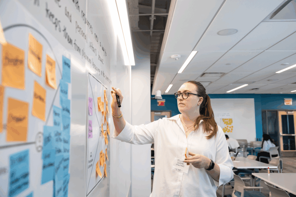 Photo of Eidos team member Julia Votto writing on a whiteboard covered in sticky notes