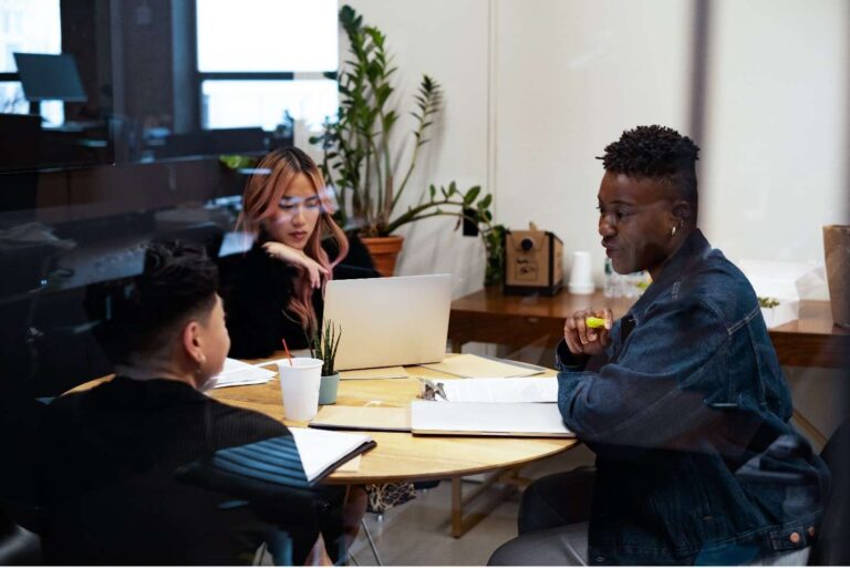 Three individuals brainstorm around a circular table