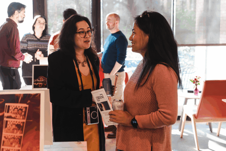 Photo of Dr. Jennifer Tran speaking to an attendee at her gallery event